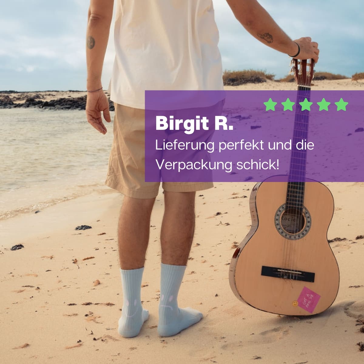 Mann mit einer Gitarre in der Hand am Strand und hellblauen Smile Sportsocken von PATRON SOCKS