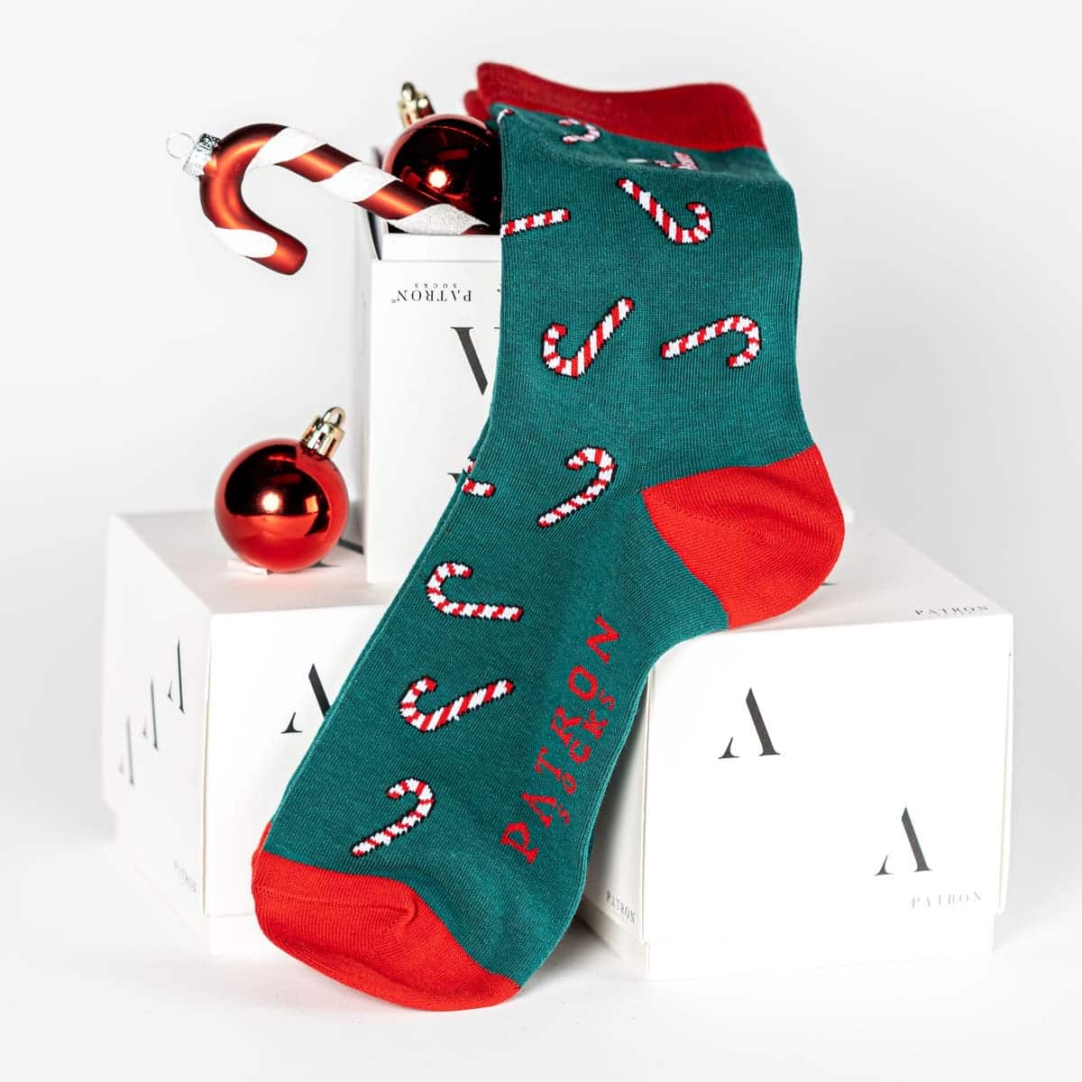 mit Weihnachtskugeln dekorierte Box und grüne Zuckestangen Socken von PATRON SOCKS