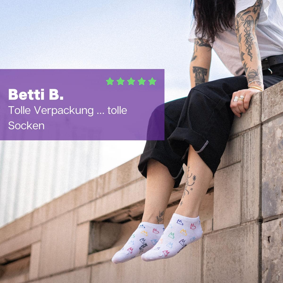 Frau auf Mauer sitzend mit weißen Kölner Dom Sneaker Socken von PATRON SOCKS